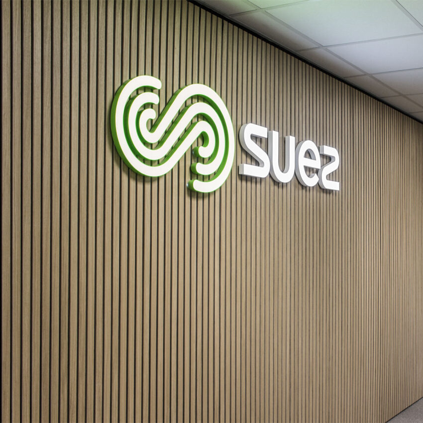 SUEZ - logoskilt på trælistevæg